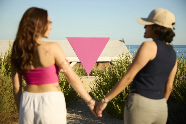 Una pareja de chicas ante el monumento LGTBI de Sitges