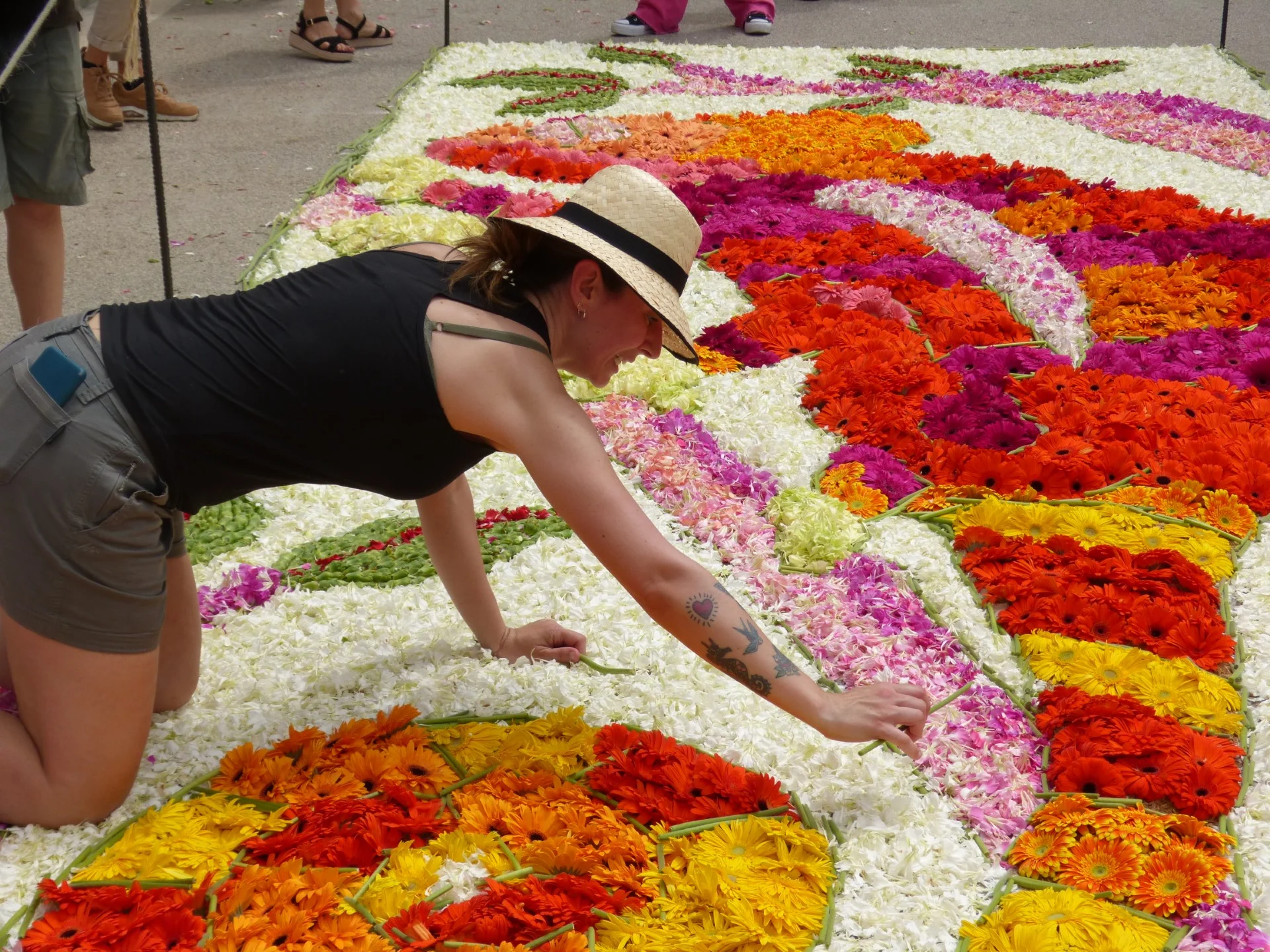 Una mujer coloca flores de colores para crear una catifa de flores durante la festividad del Corpus en Sitges.